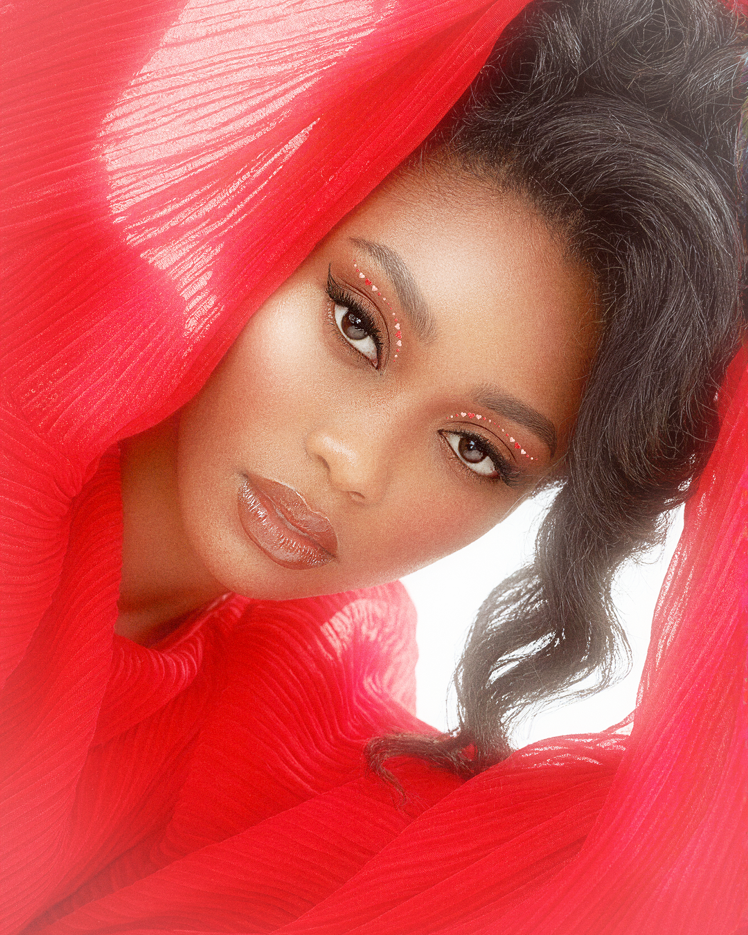 Woman with red fabric partially covering her face against a white background