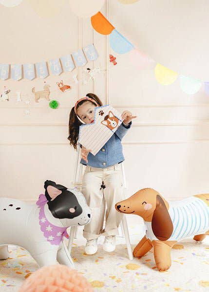 Child holding a plush toy in a room with colorful decorations and toys on the floor.