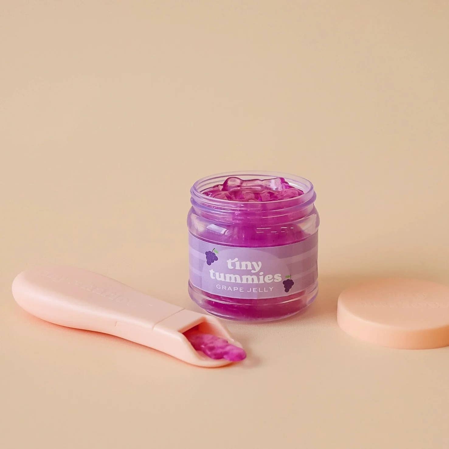 Pink jelly in a jar with a pink spoon on a beige background