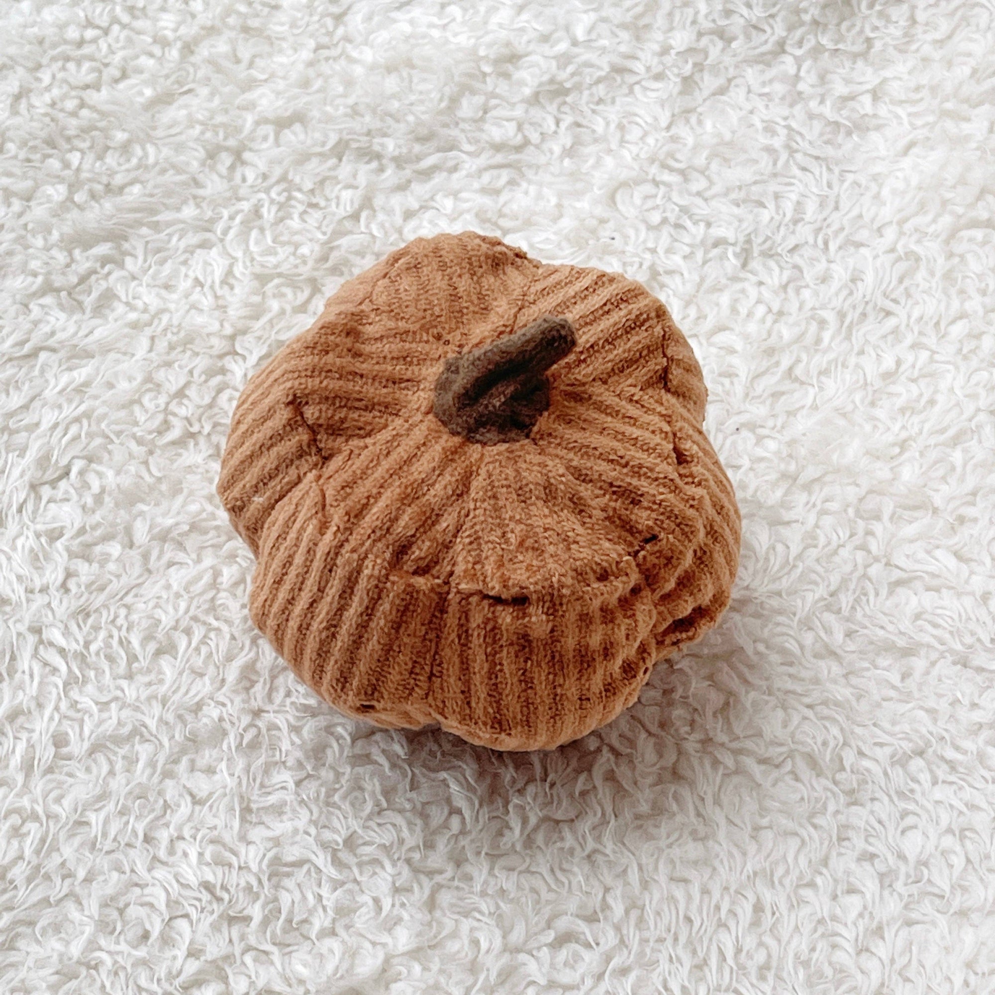 Orange textured pumpkin on a white textured surface