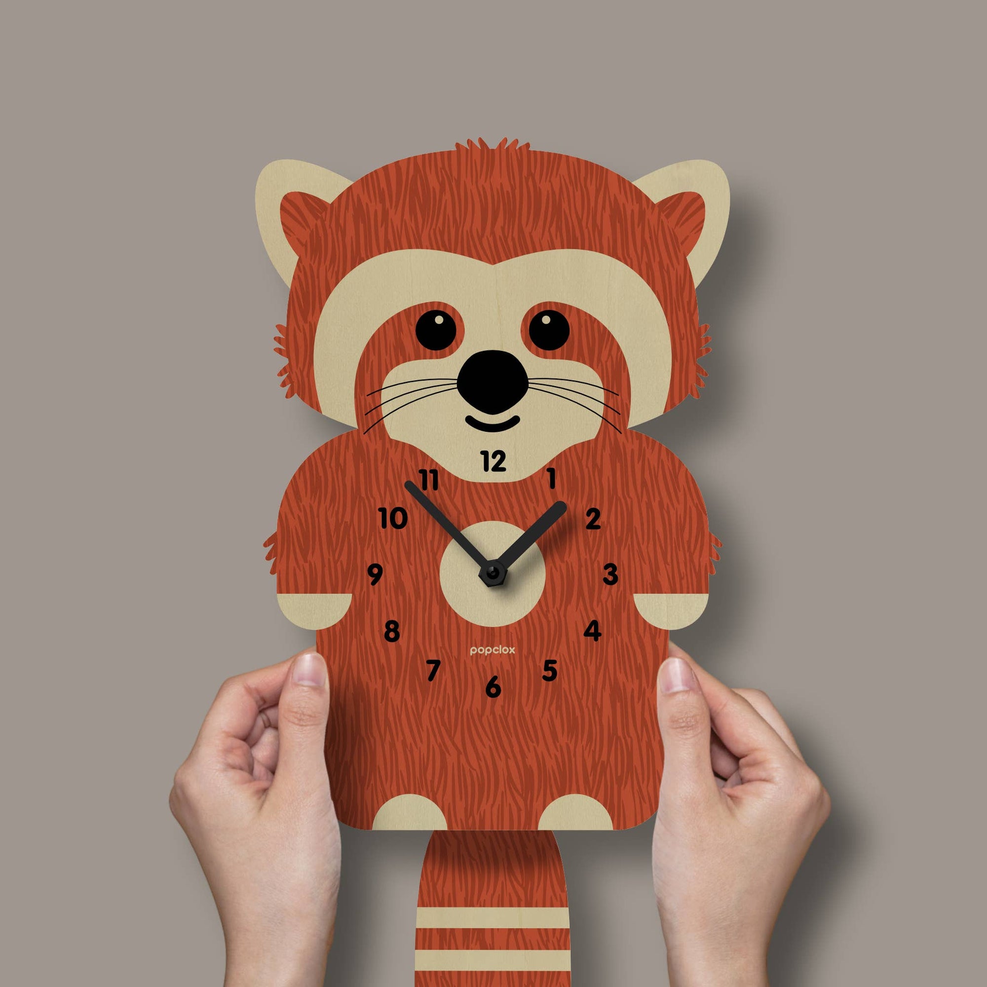 Wooden clock shaped like a red panda held by hands against a plain background