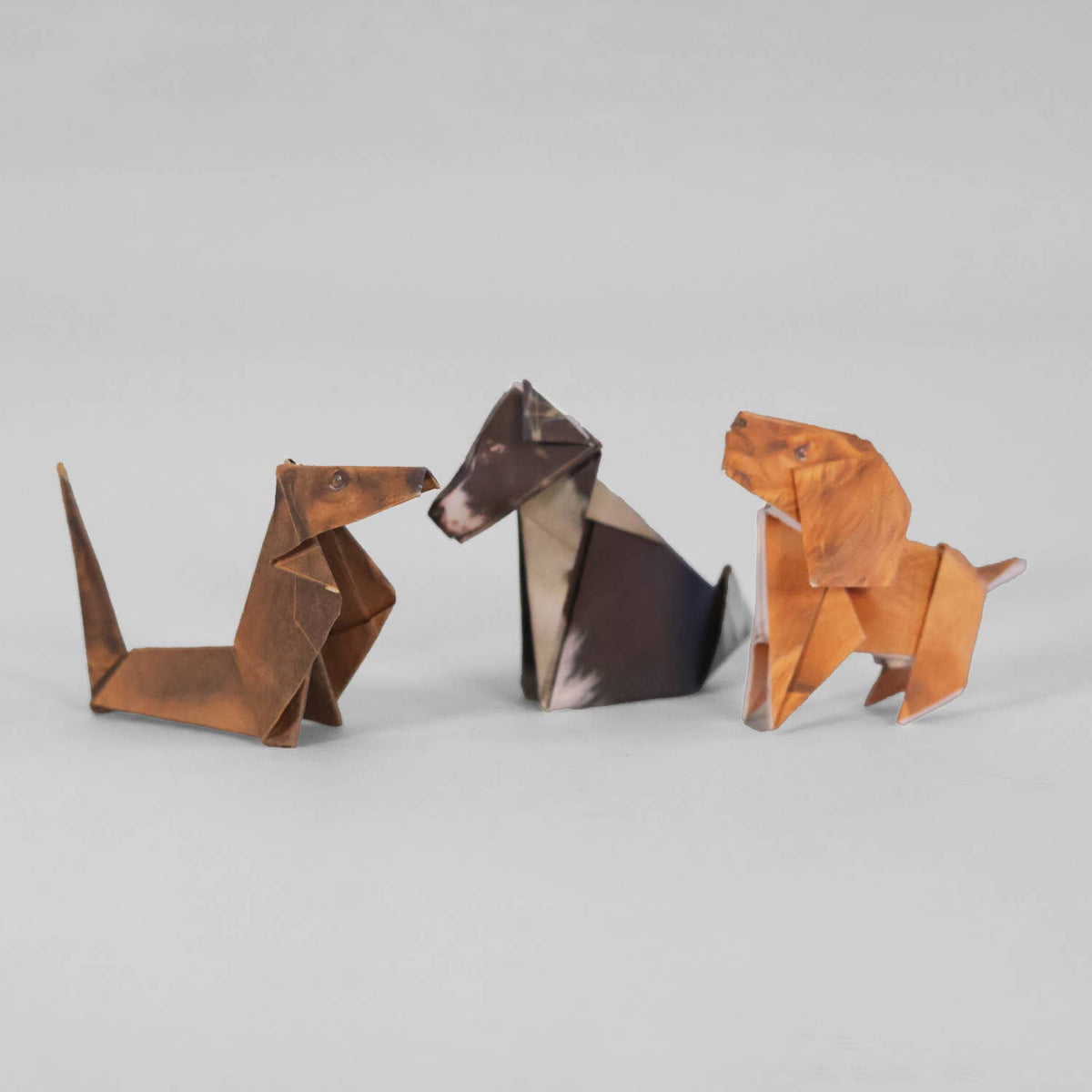 Three origami dogs of different colors on a light gray background