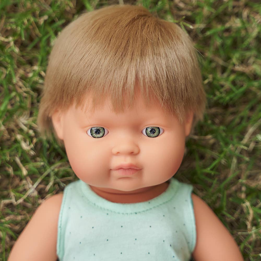 Doll with blonde hair and blue eyes wearing a light green sleeveless top against a grassy background