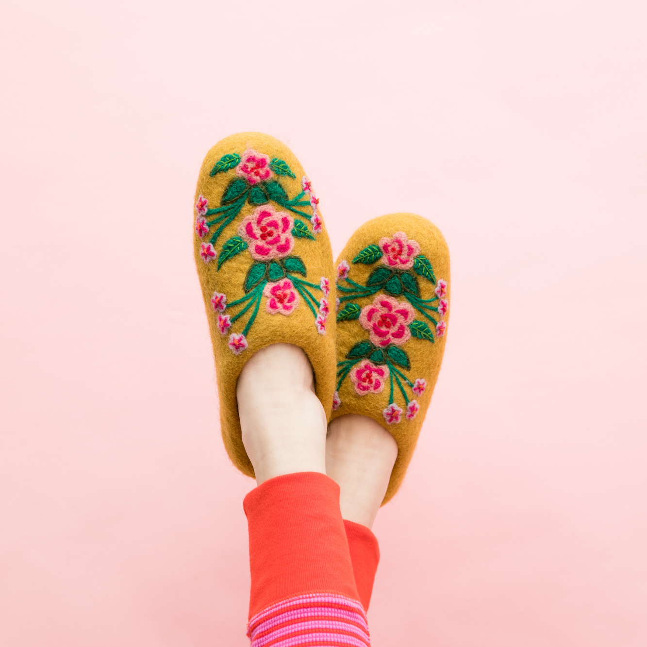 Yellow floral slippers on feet with pink background