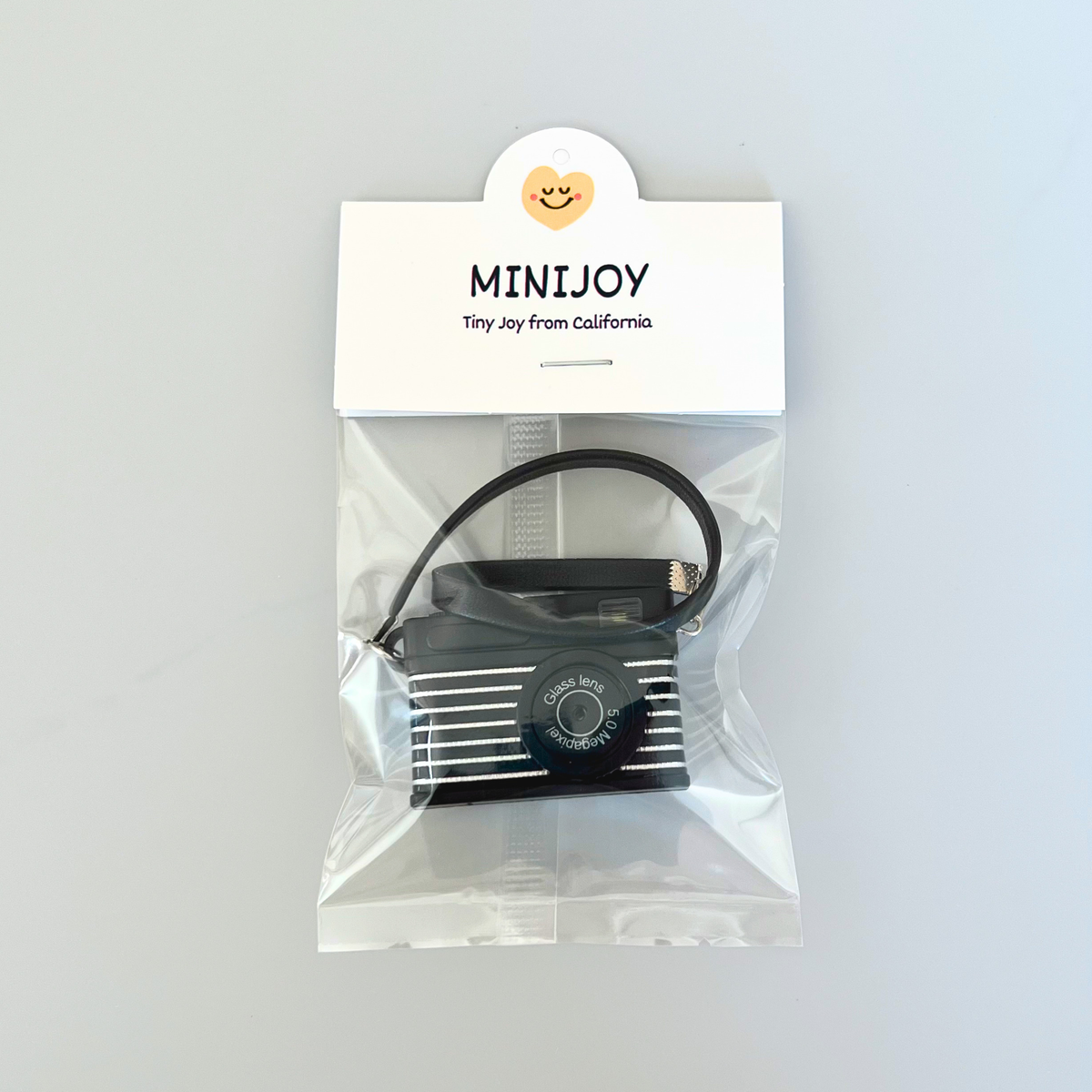 Black electronic device in clear packaging with 'MINIJoy' label on a light gray background