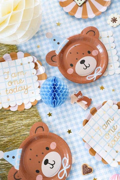 Children's birthday party decorations with bear-themed plates and cards on a checkered tablecloth.