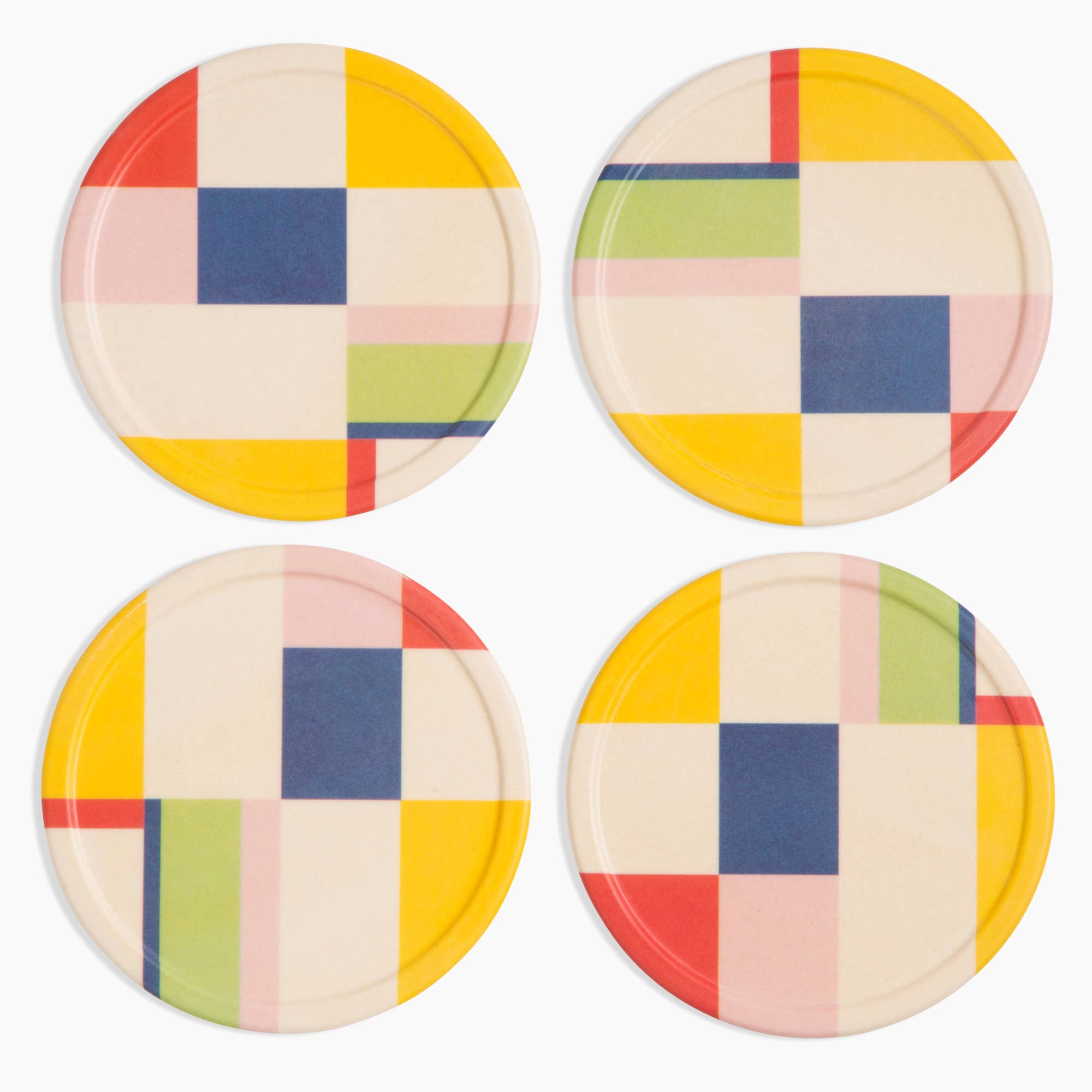 Four round coasters with a colorful checkered pattern on a white background