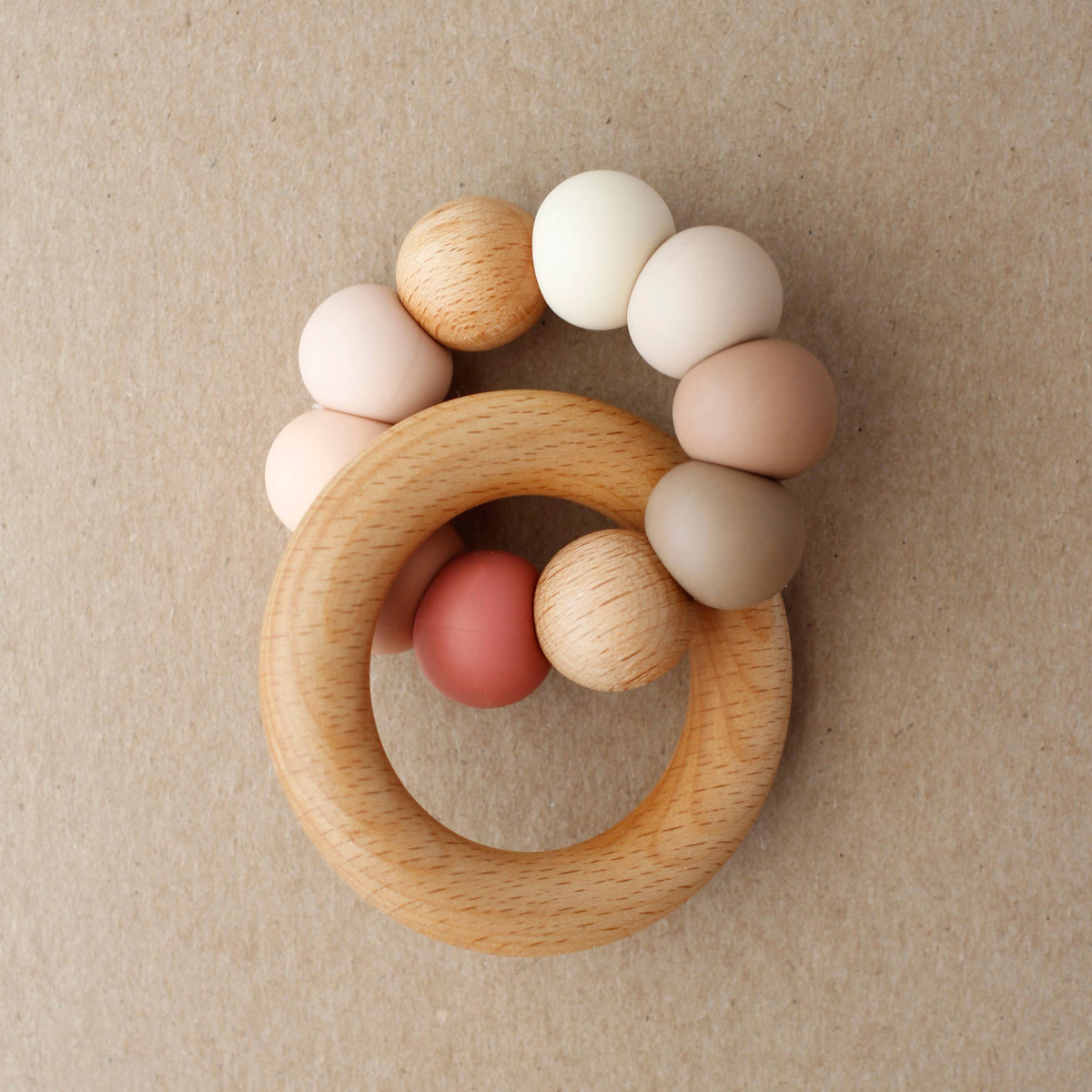 Wooden teething ring with colorful beads on a beige background
