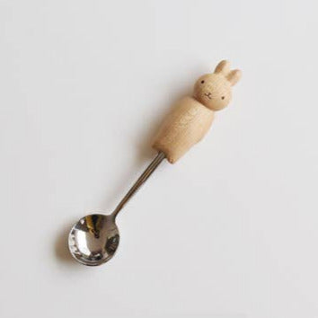Spoon with a wooden handle shaped like a rabbit on a light gray background