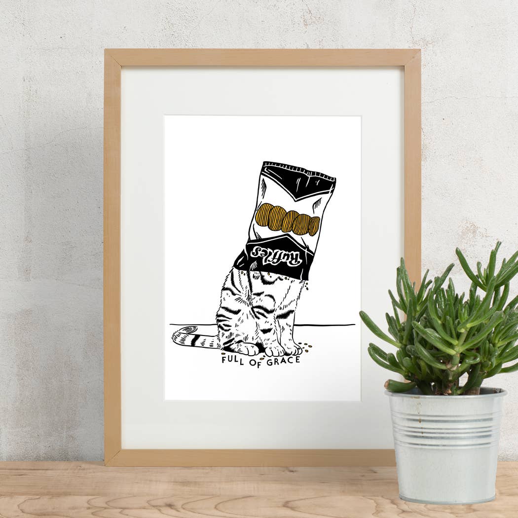 Framed artwork of a cat with a bag labeled 'Full of Grace' next to a potted plant on a wooden surface.