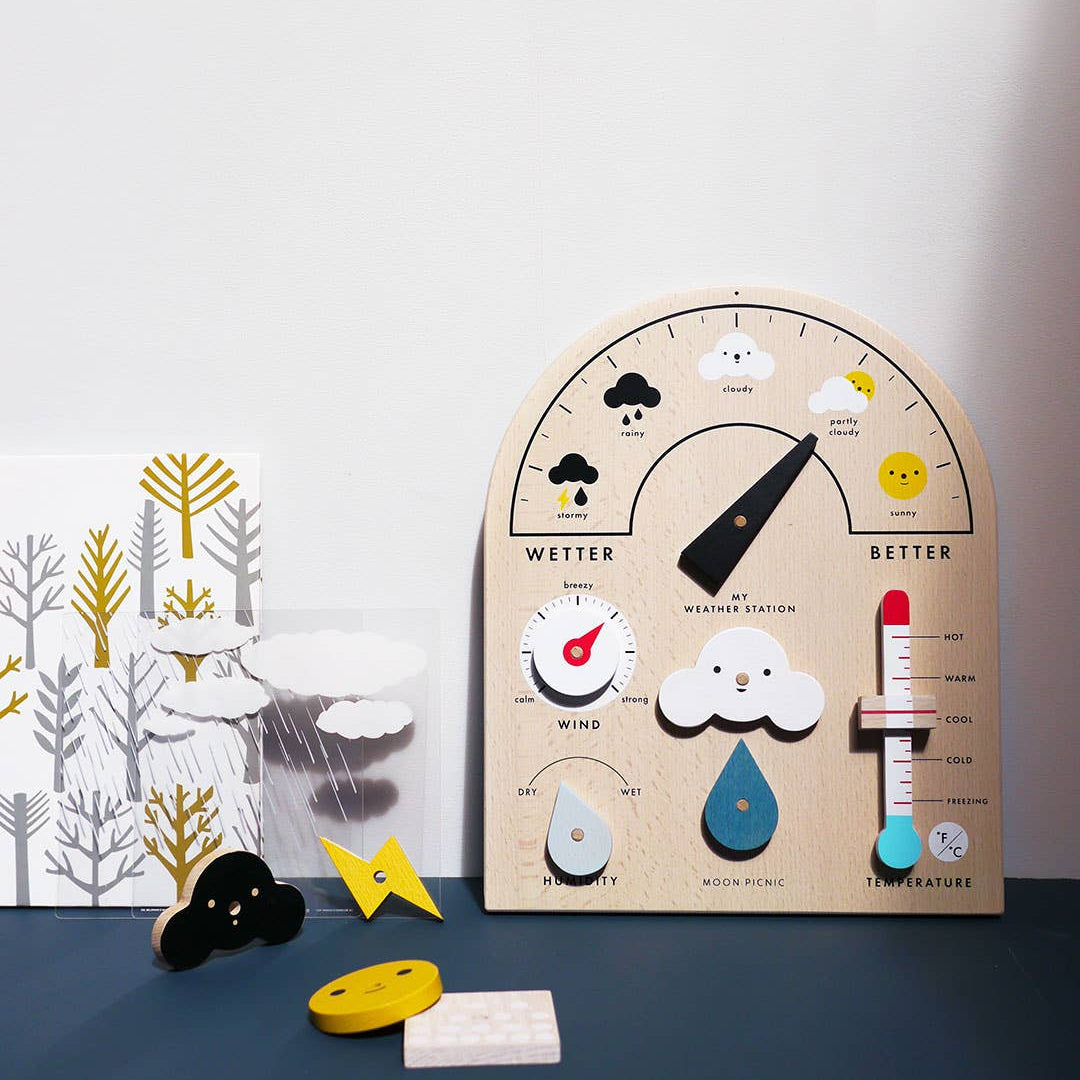 Wooden weather station toy with various elements on a blue surface