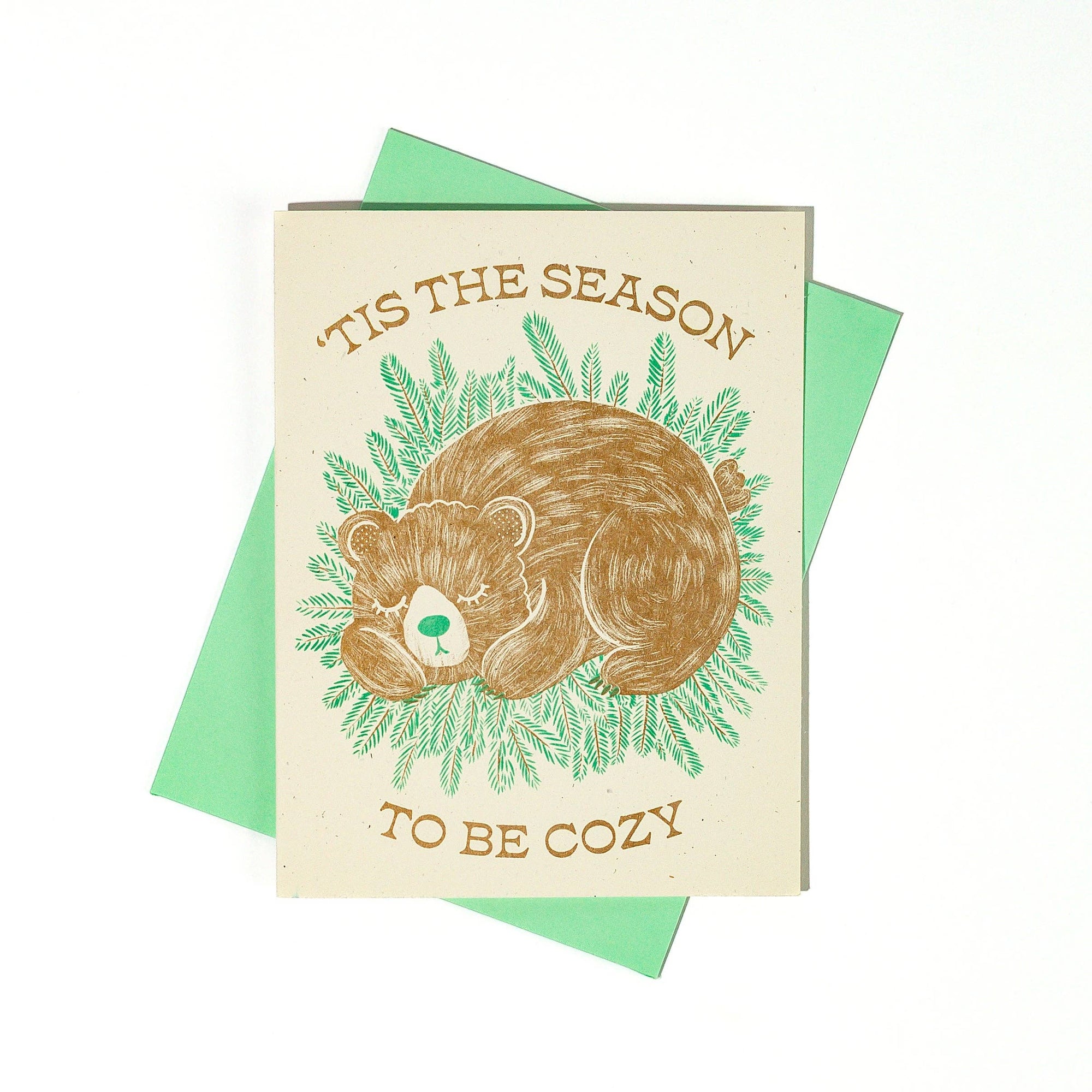 Greeting card with bear illustration and text 'Tis the season to be cozy' on a white background.