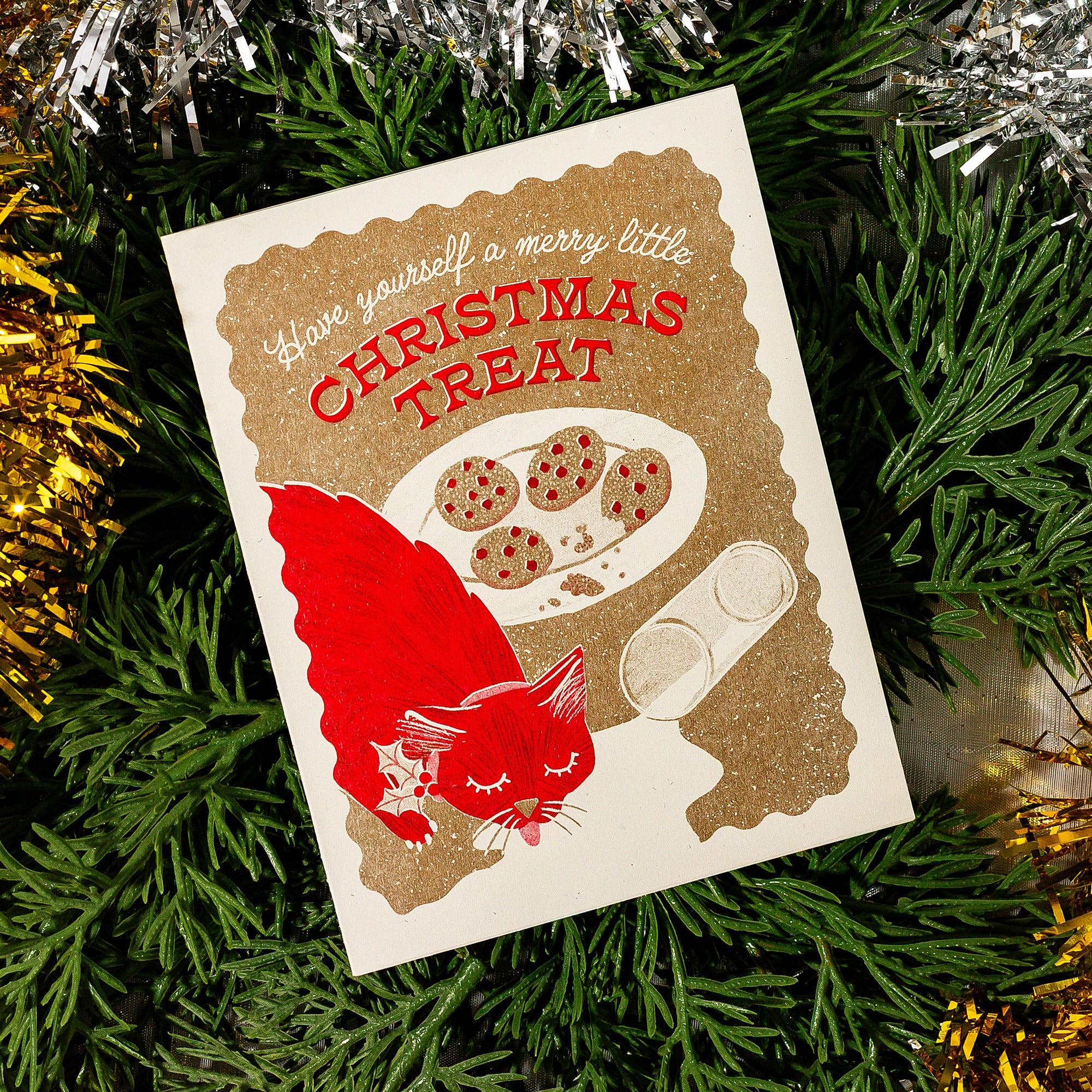 Christmas-themed card with a red cat and cookies on a green leaf background