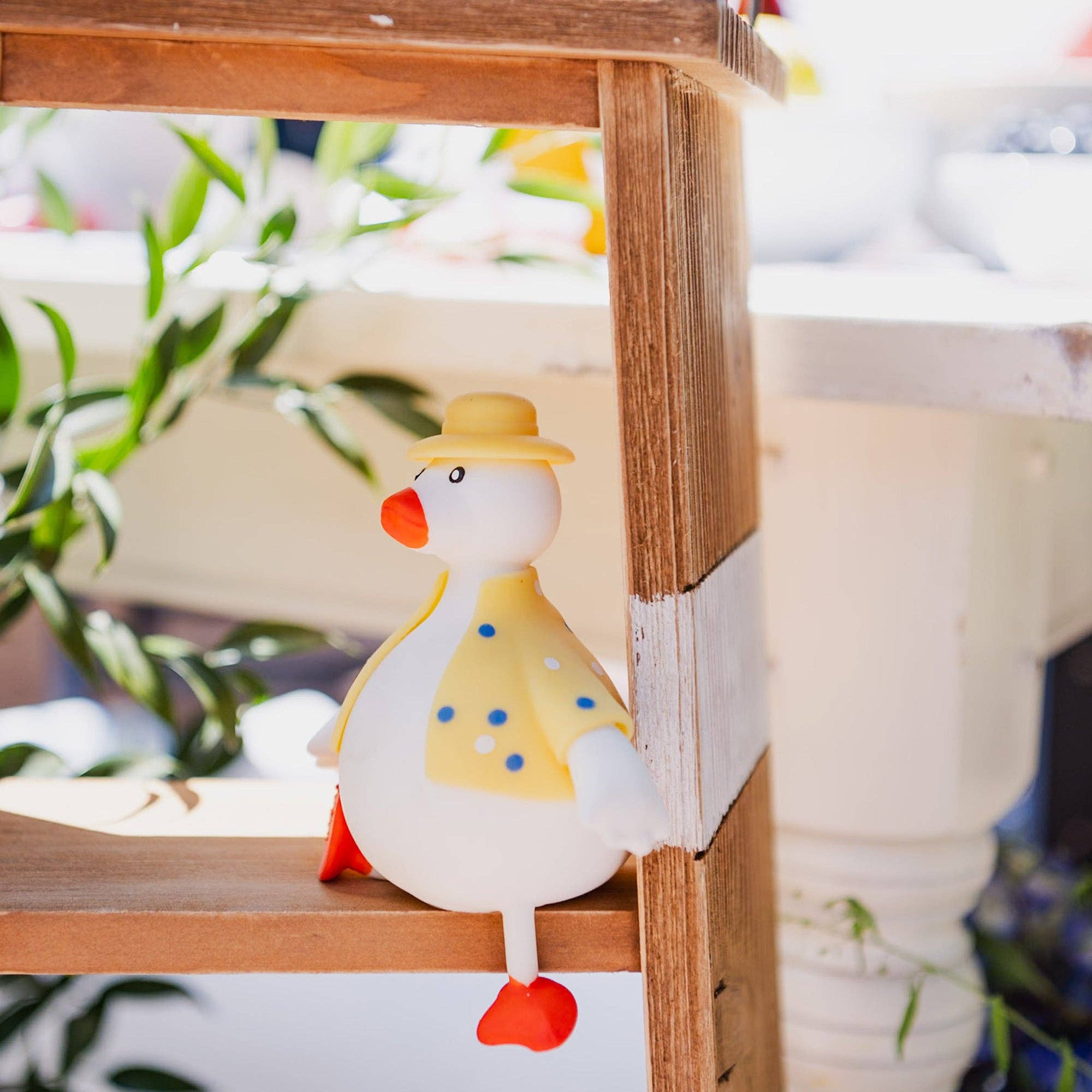 Decorative duck figurine with a yellow hat on a wooden surface