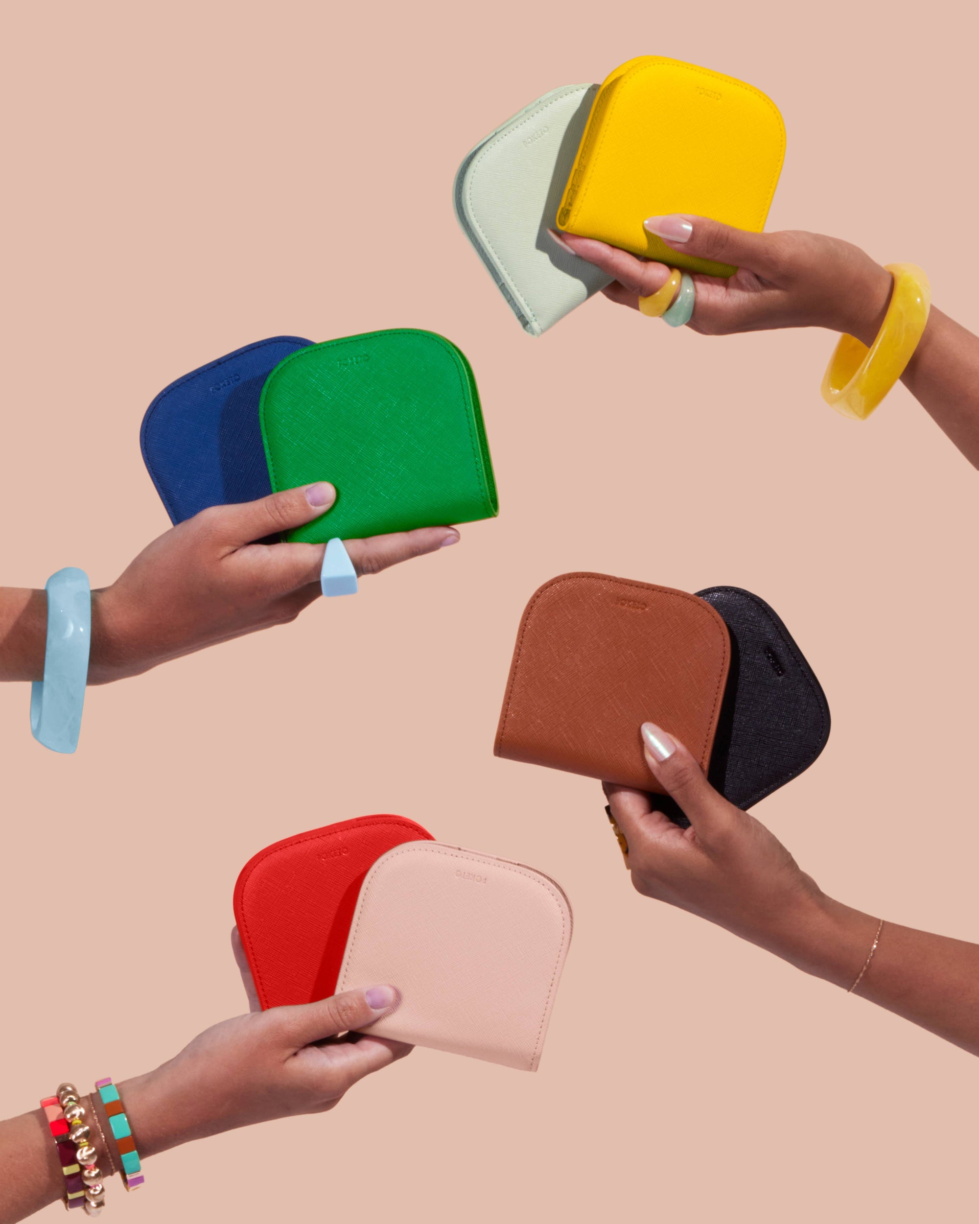 Hands holding colorful wallets against a beige background