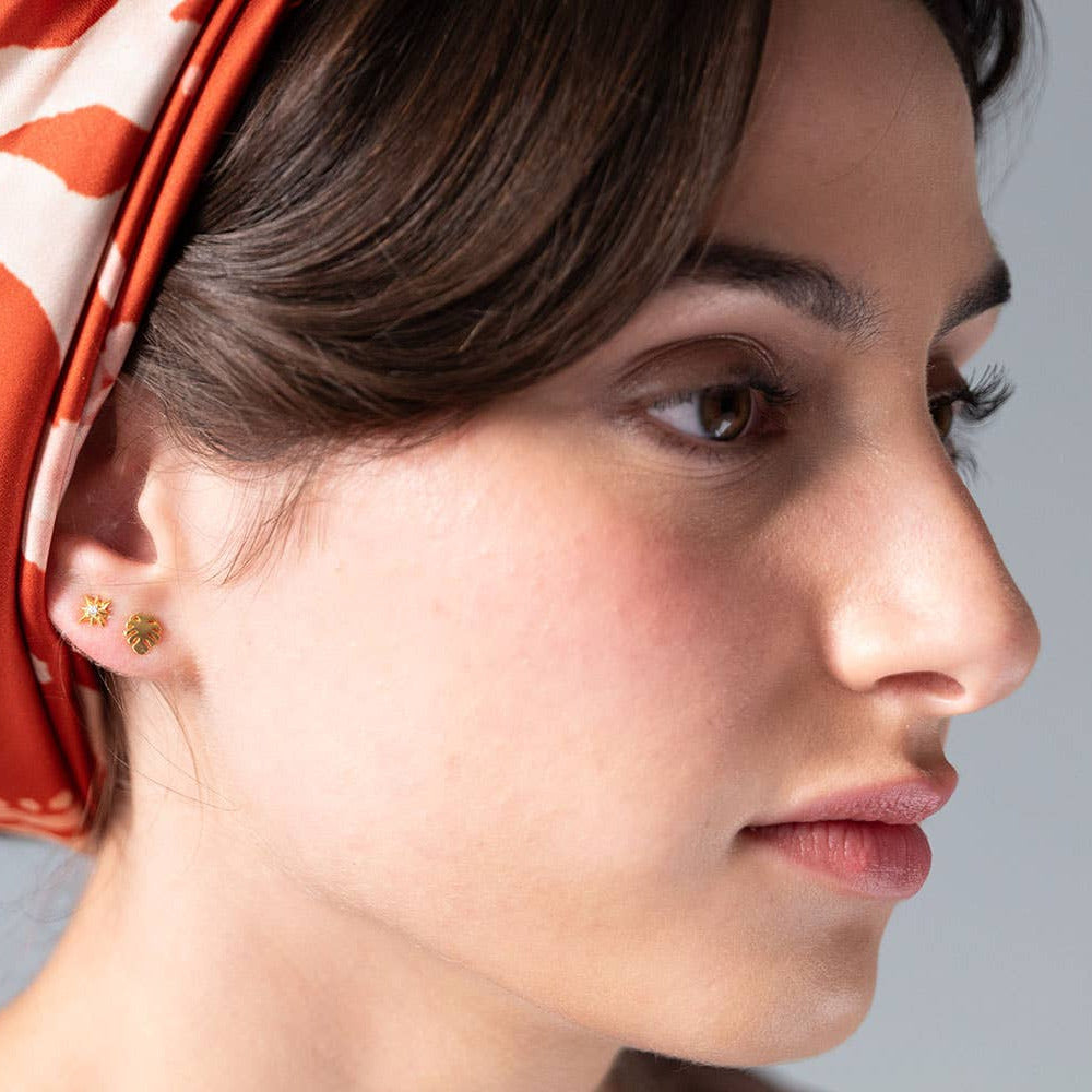 Close-up of a woman's face wearing gold earrings with a red and white patterned headscarf.
