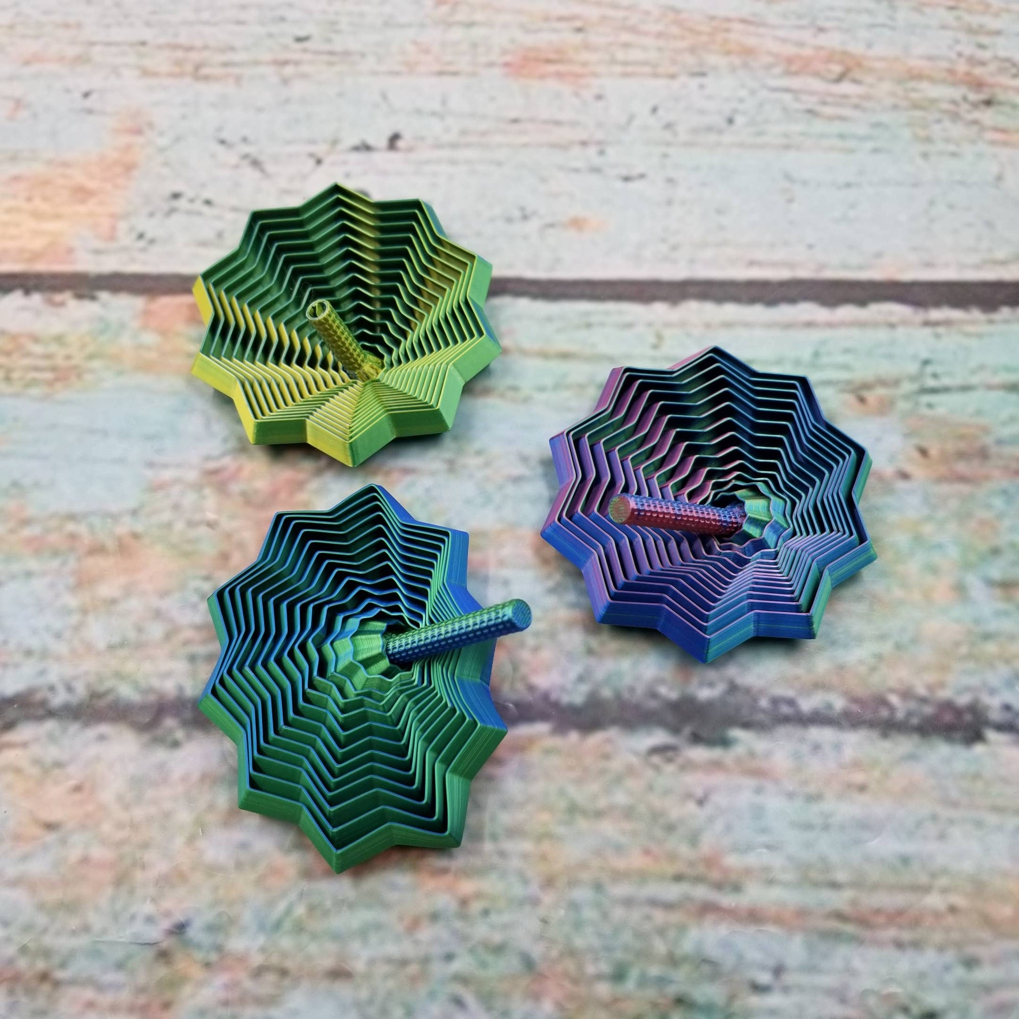 Three colorful geometric sculptures on a textured surface