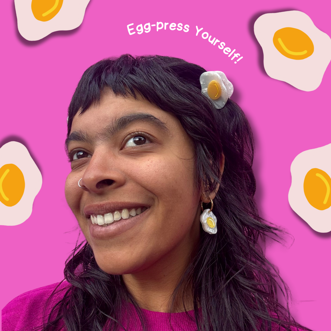Person with egg-shaped earrings and a pink background with fried egg illustrations and text.