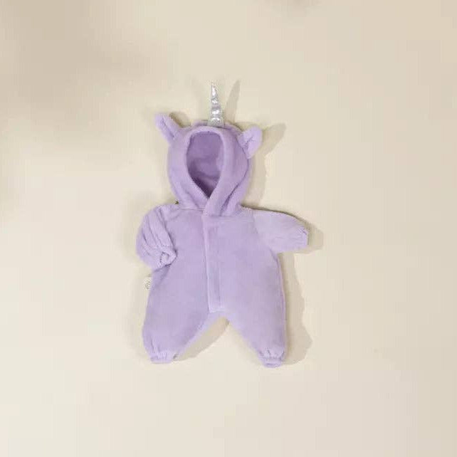 A small lavender plush unicorn toy with a horn and ears, photographed against a warm cream background.