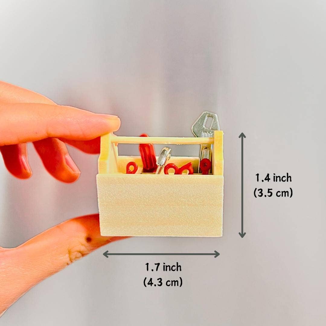 Hand holding a small wooden tool set with measurements indicated on a gray background