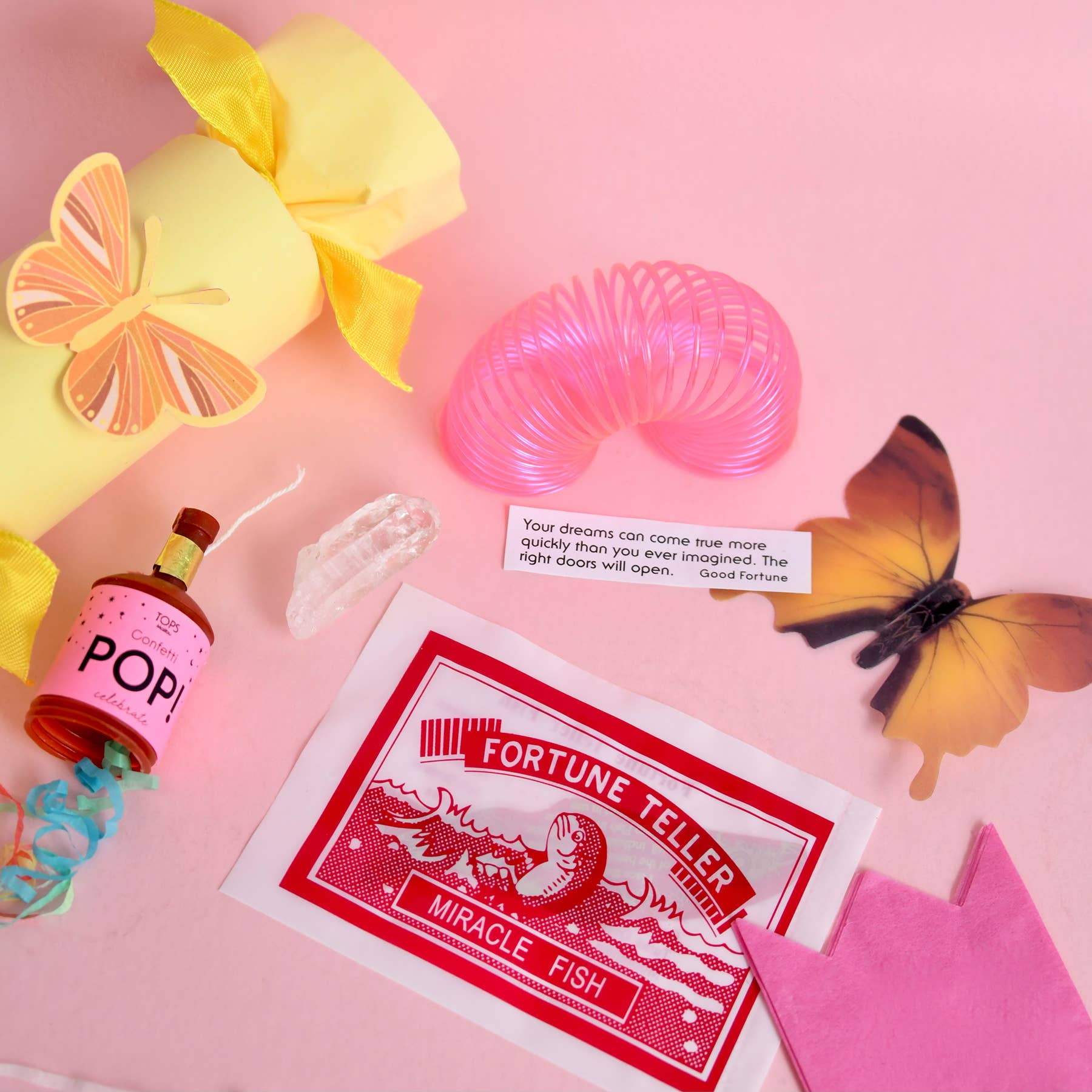 Colorful objects including a fortune teller card, pop bottle, and butterfly on a pink background
