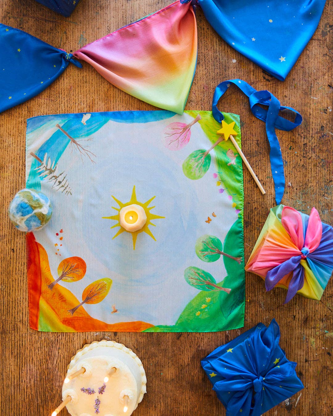 Colorful kite on a wooden surface with ribbons and other kite parts.