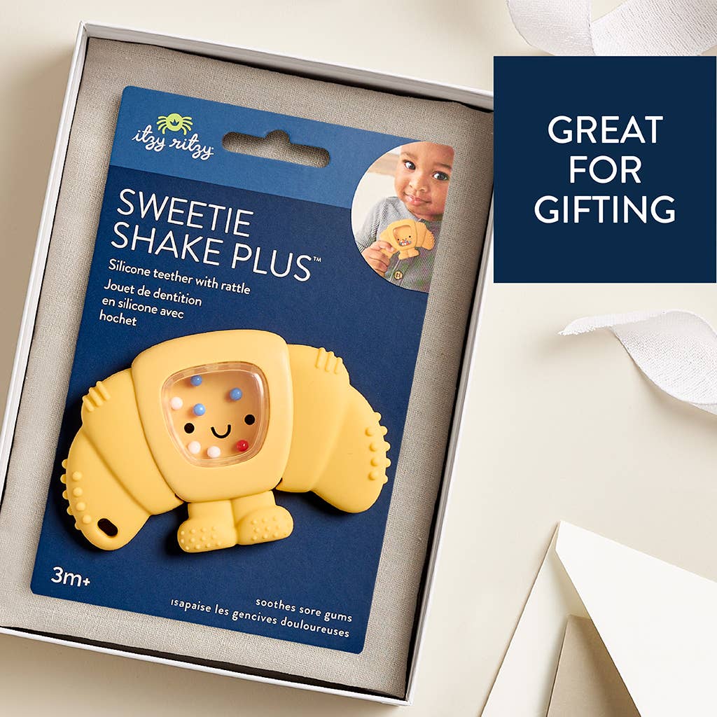 Yellow pastery-shaped silicone teether with packaging on a white surface