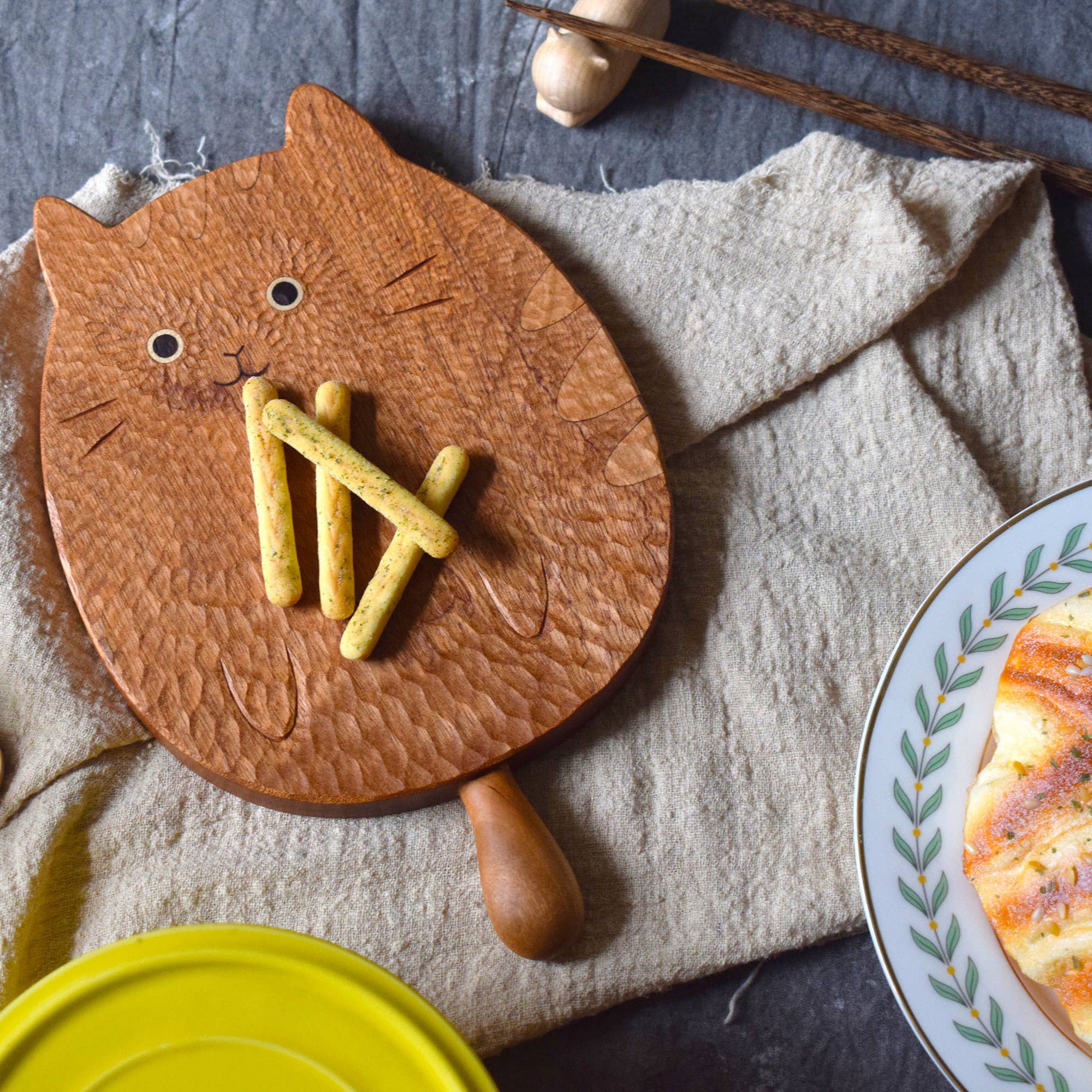 Wooden cat-shaped cutting board with mustard on a textured surface