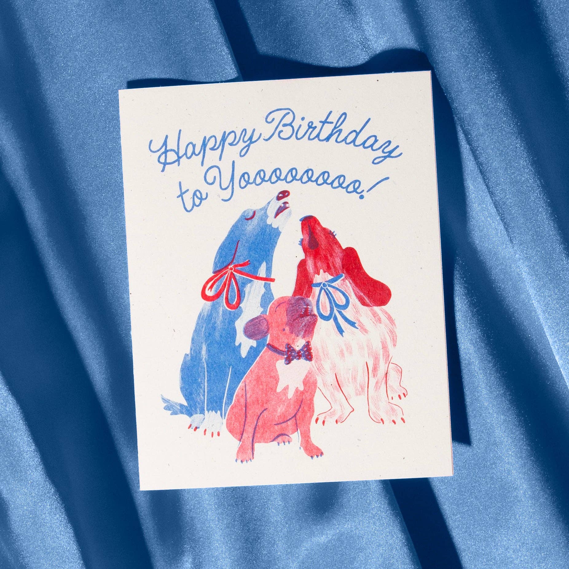 Birthday card with colorful dogs and 'Happy Birthday to Yoooooo!' text on a blue fabric background