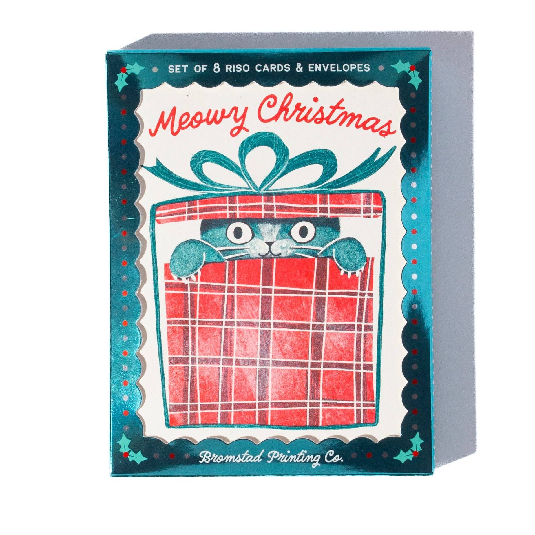 A boxed set of Riso cards and envelopes featuring a Christmas-themed illustration. The front shows a teal decorative border, red script text reading 'Meowy Christmas,' and a red gift box with a cat peeking out.