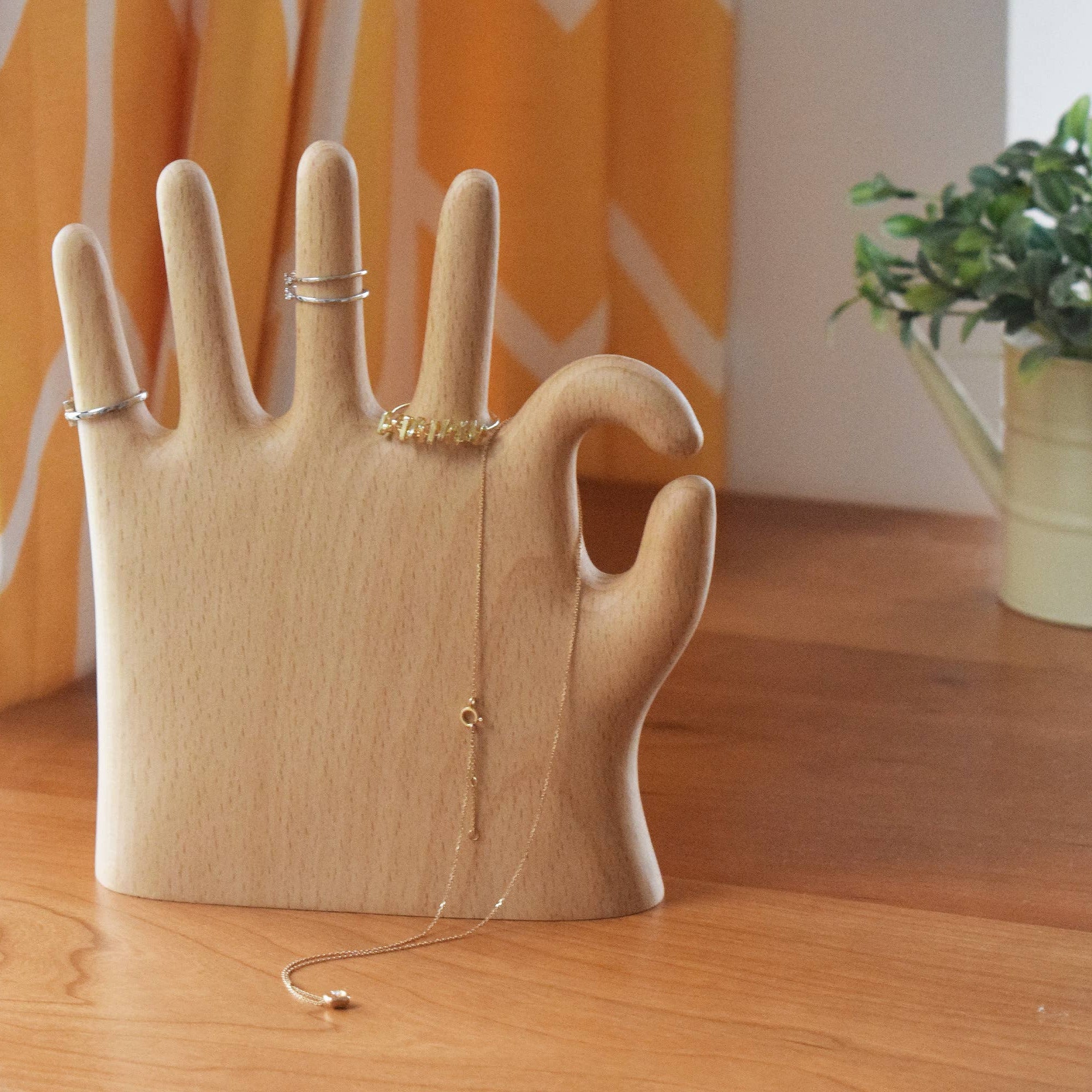 Wooden hand-shaped jewelry holder with rings on a wooden surface
