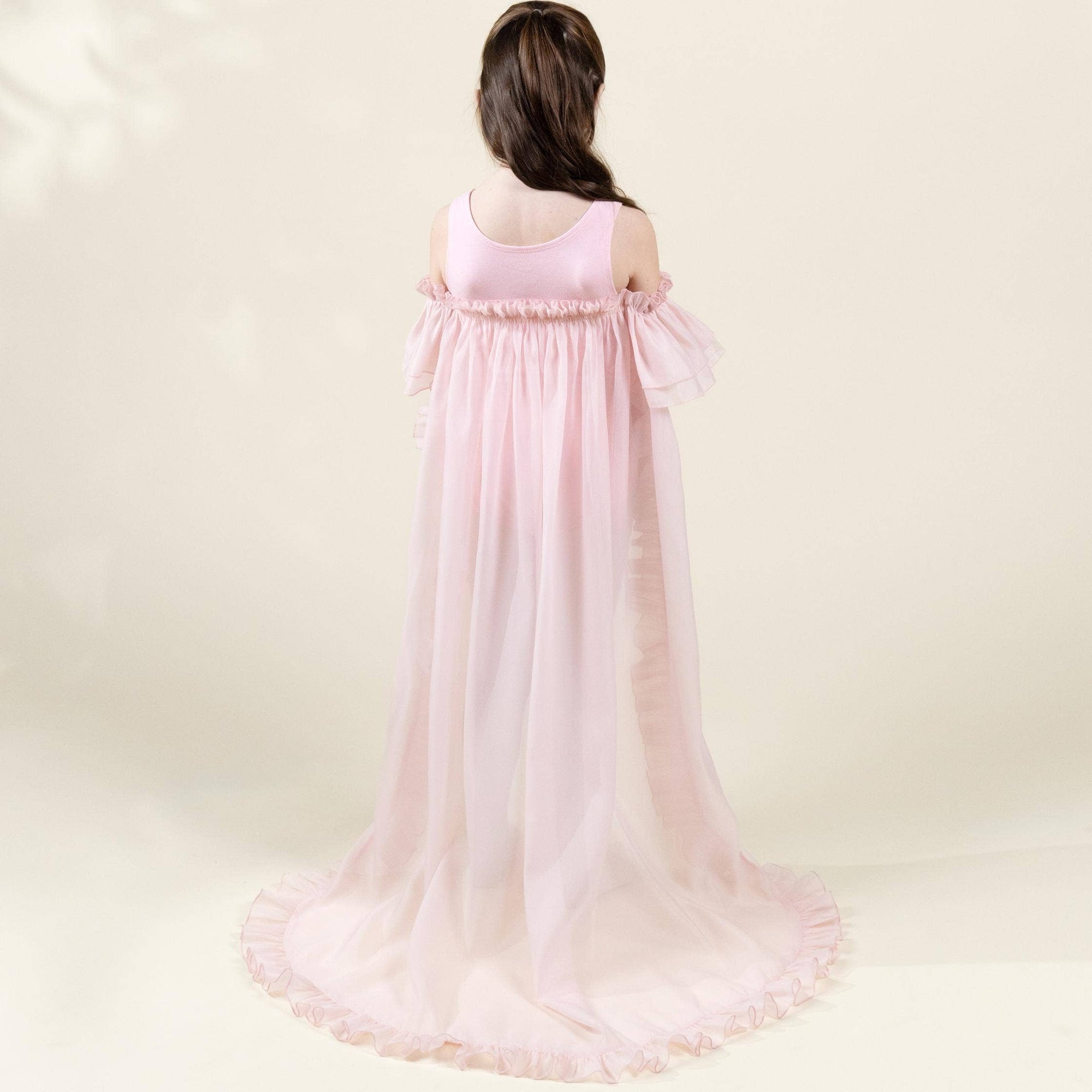 Girl wearing a pink flowing dress against a white background