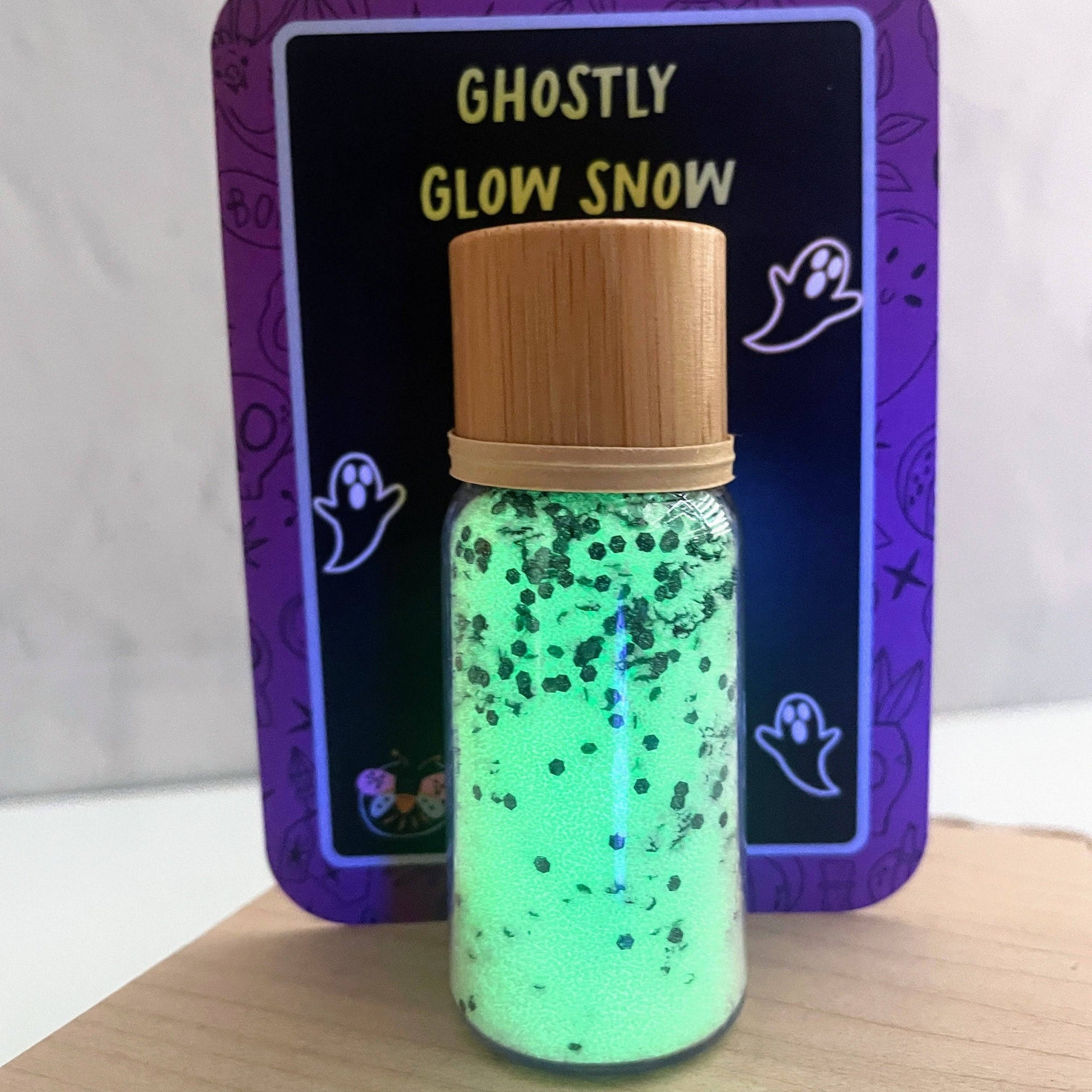Bottle of ghostly glow snow with a purple label featuring ghost illustrations on a white background.