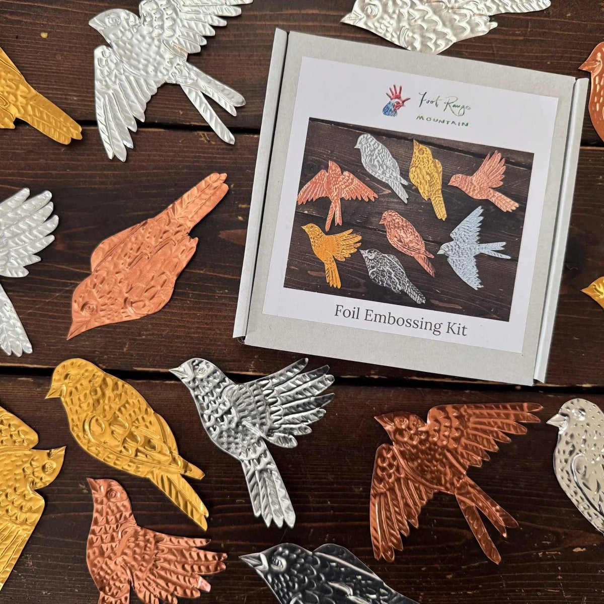 Foil embossing kit with bird designs on a wooden surface