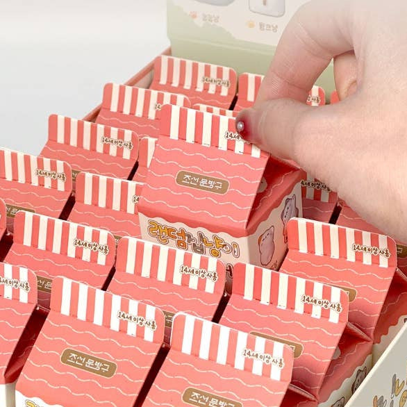 Stack of red and white striped boxes with a hand reaching for one, on a light gray background.
