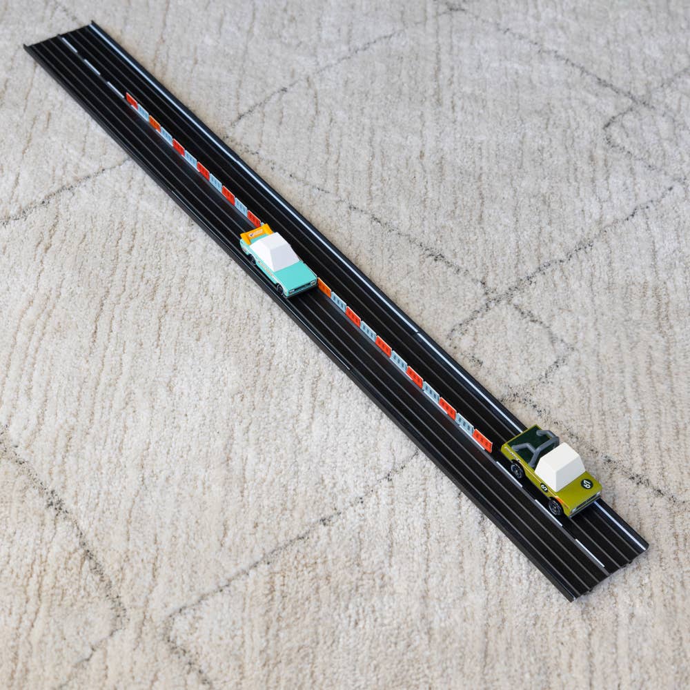 Toy train set on a track with two toy cars on a textured surface
