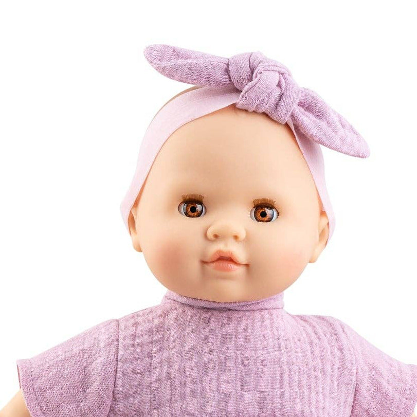 Baby doll wearing a purple dress and headband on a white background