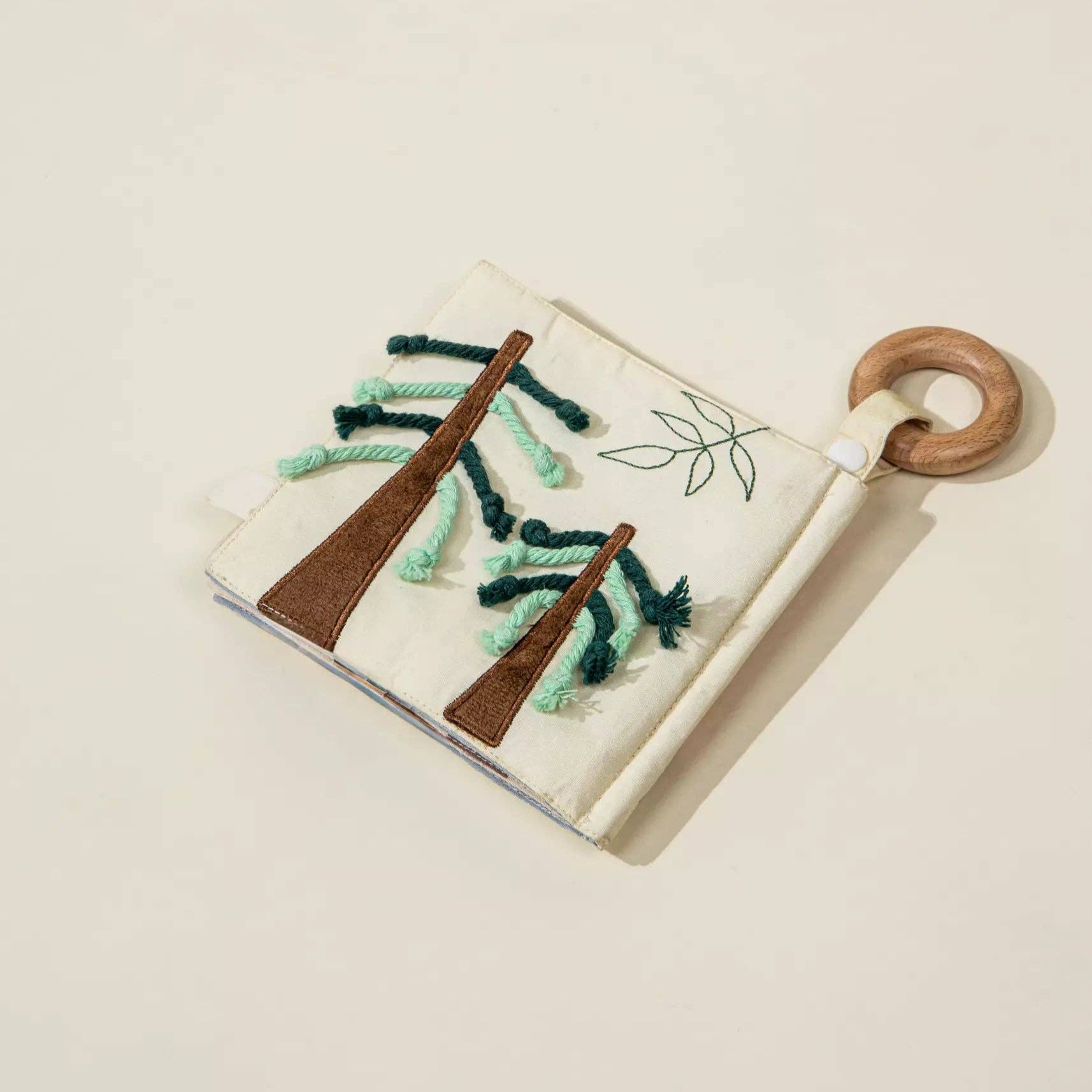 Handmade card with embroidered green leaves and wooden elements on a beige background