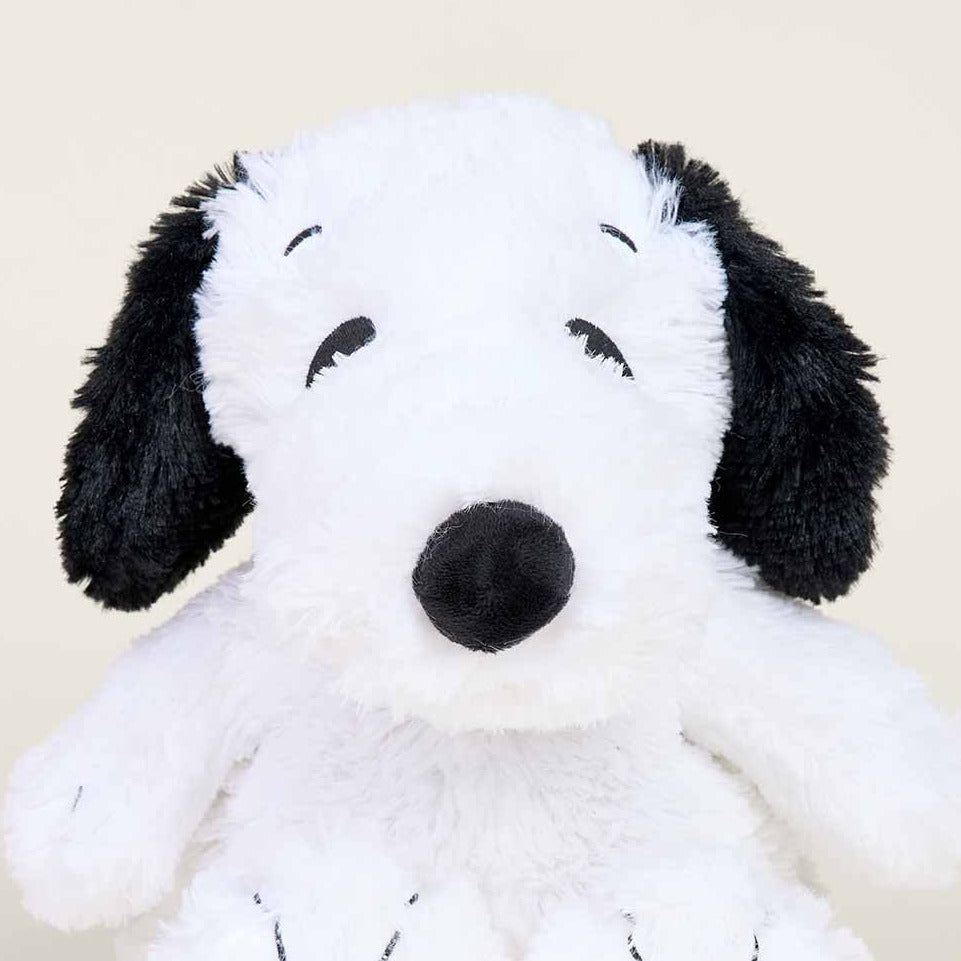 Plush toy resembling a black and white dog on a beige background