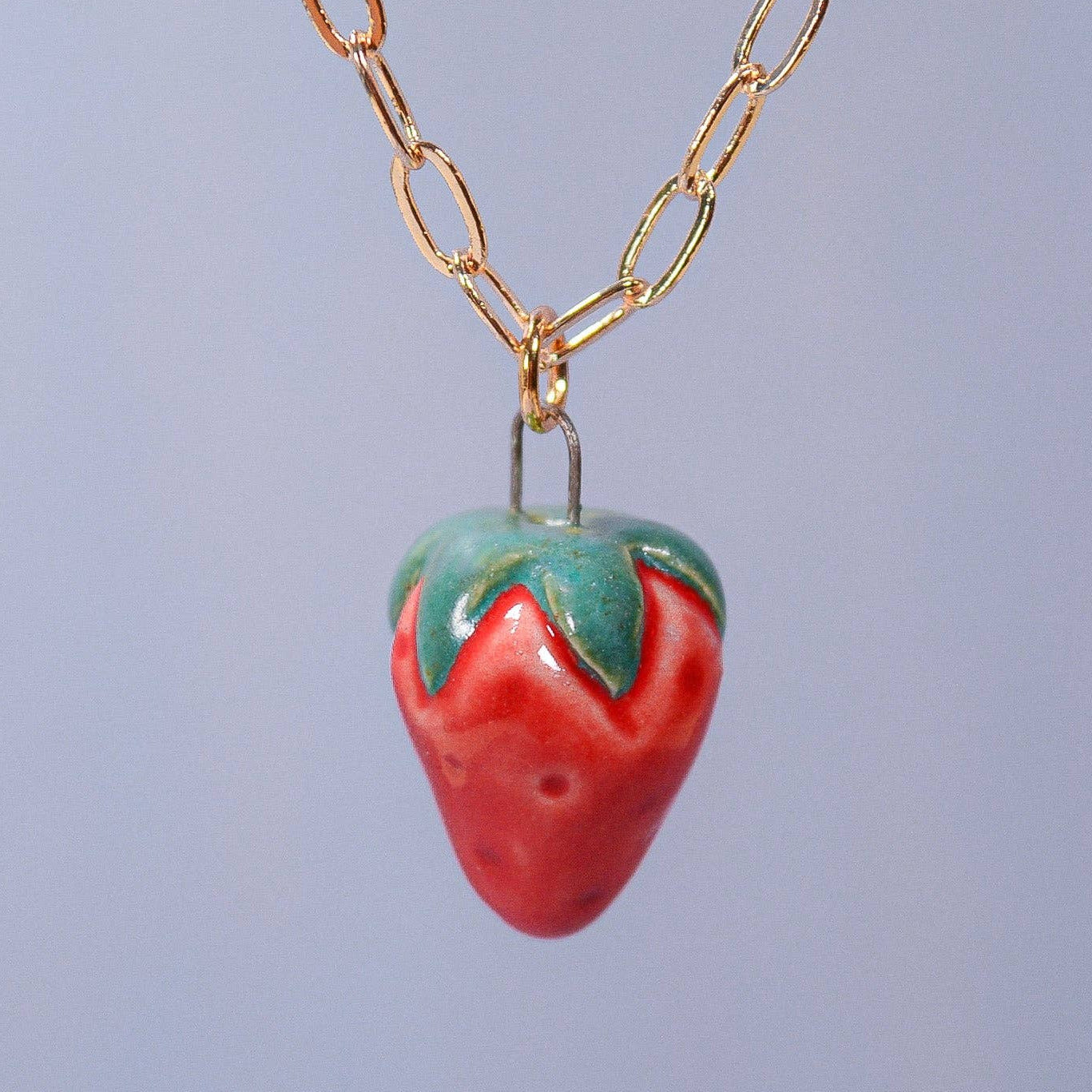 Necklace with a strawberry-shaped pendant on a light blue background