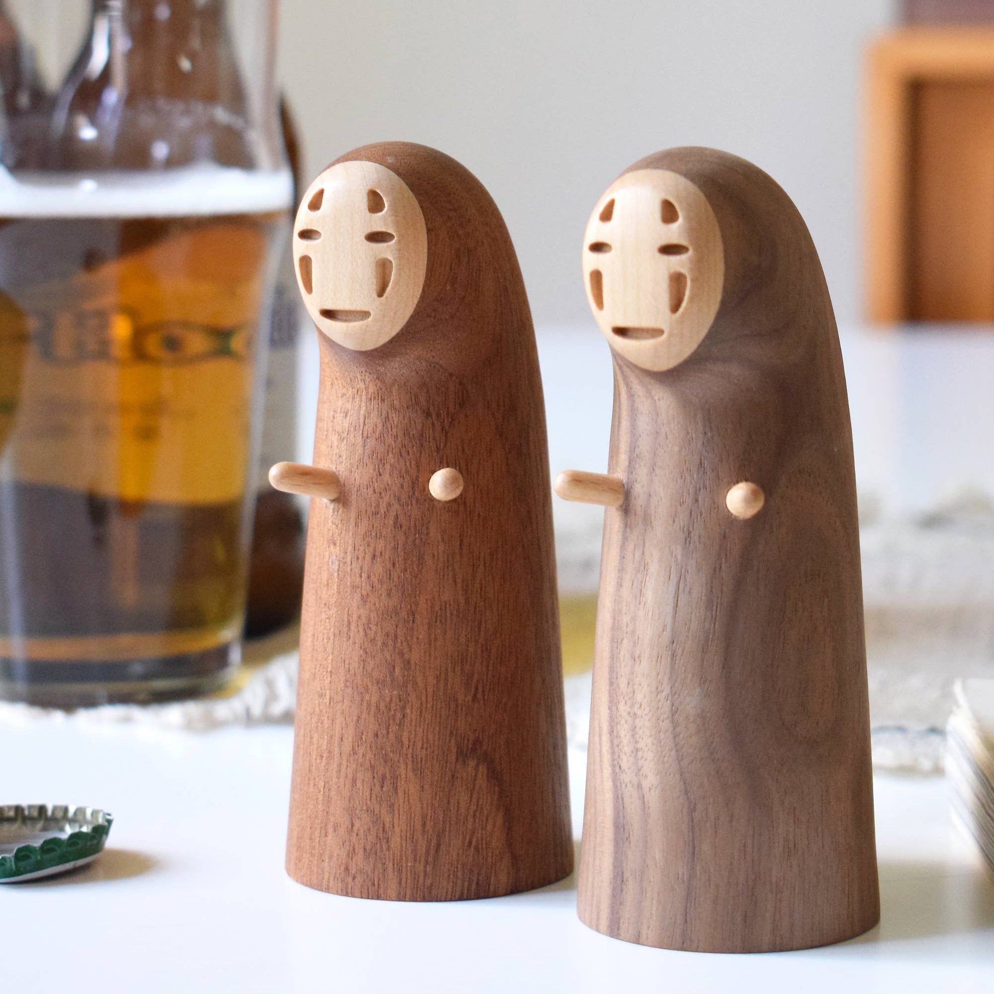 Wooden figures resembling characters from a movie on a table with a beer bottle in the background.