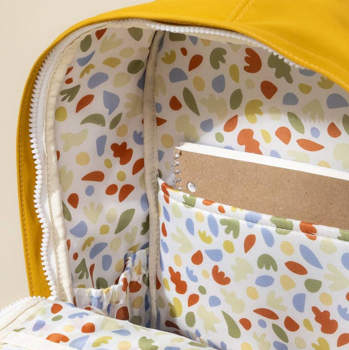Colorful polka dot fabric inside a yellow bag with a notebook.