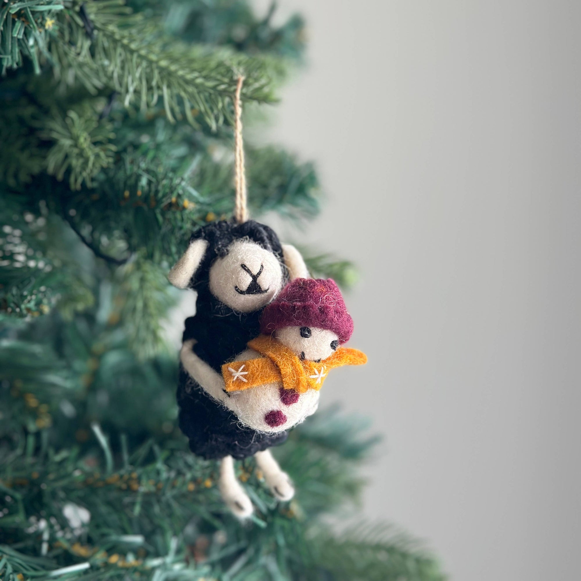 Decorative sheep ornament with a pink snowman on a Christmas tree.