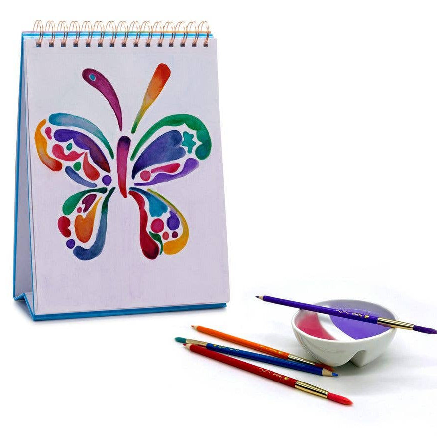 Notebook with a colorful butterfly design, paintbrushes, and a small container on a white background