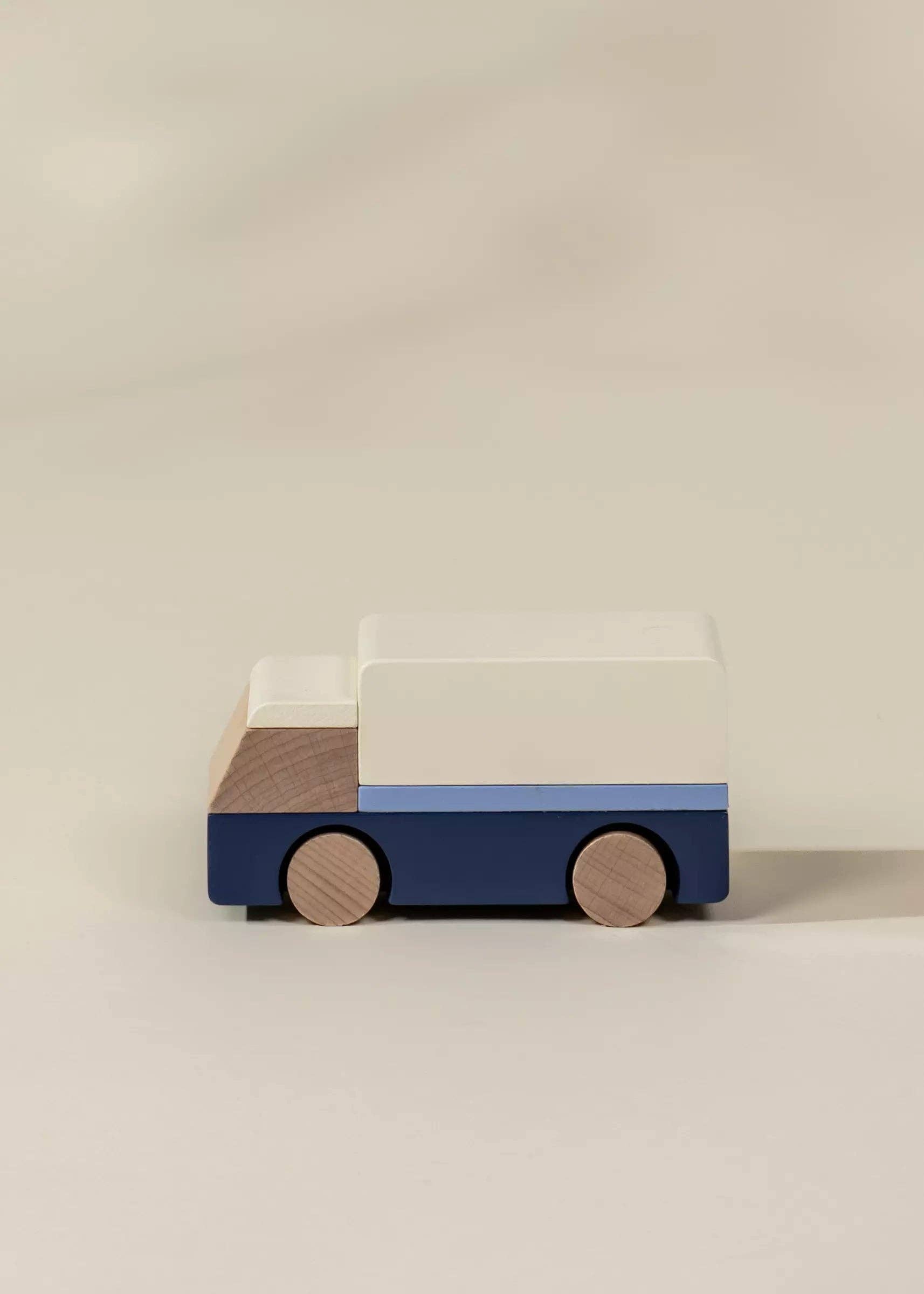Wooden toy truck with a blue base and white top on a beige background