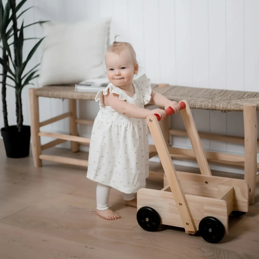 Child playing with a wooden toy in a room with a white wall and plant.