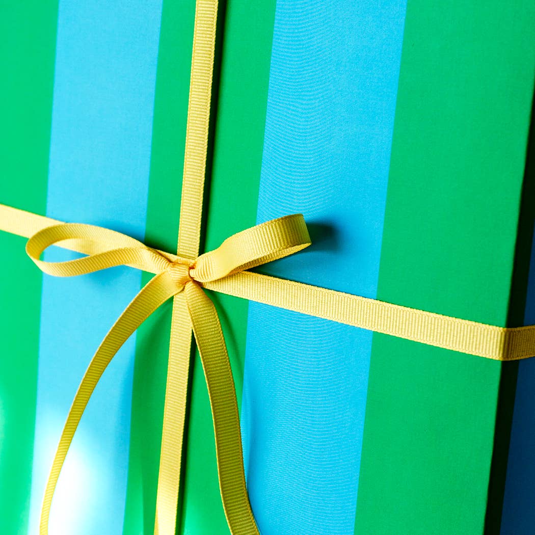 Gift box with a yellow ribbon on a green and blue striped background