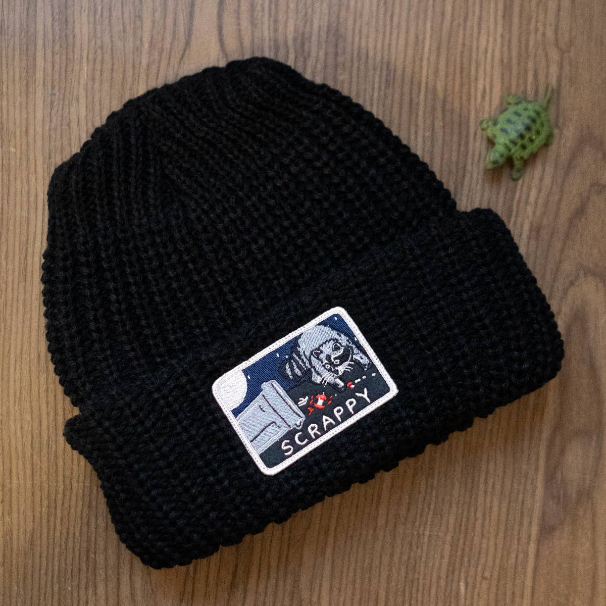 Black beanie with a patch on a wooden surface