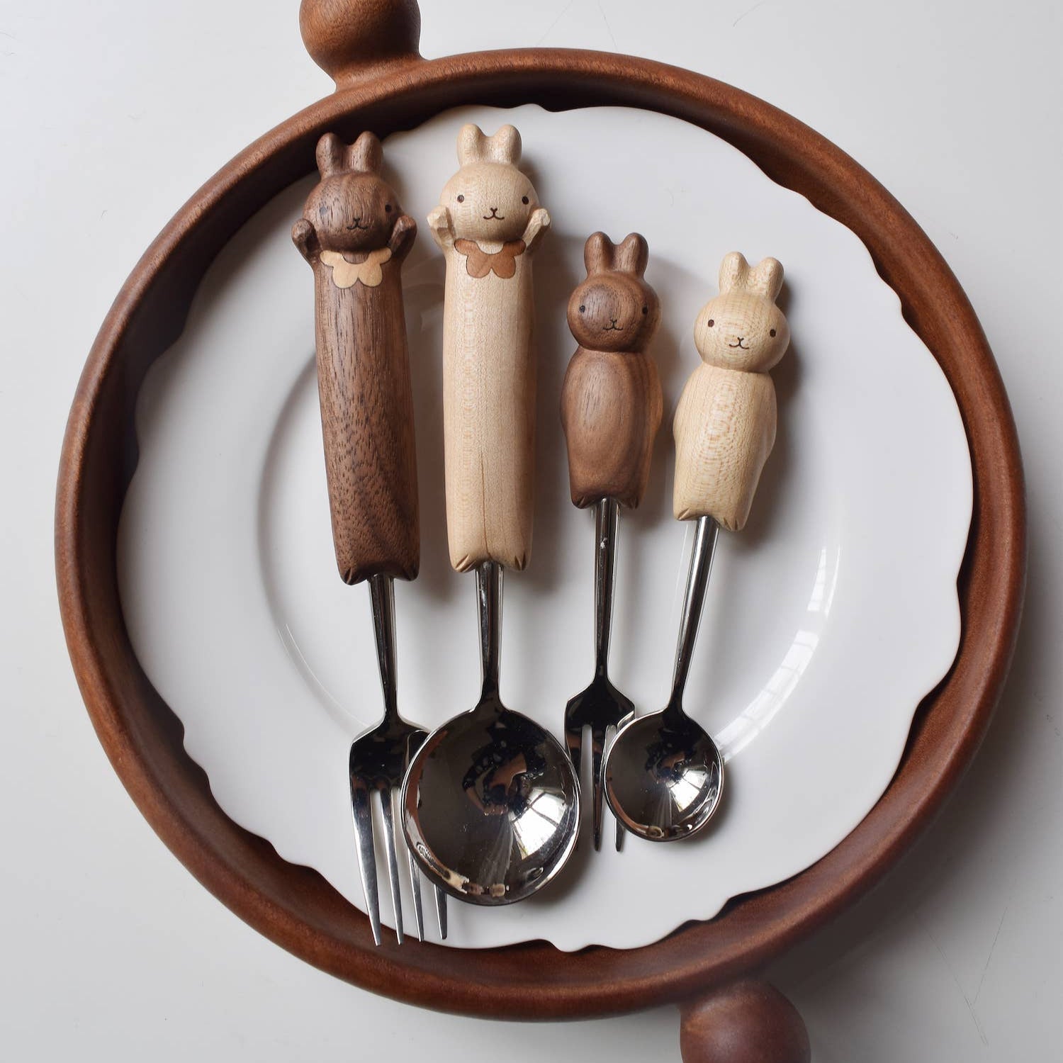 Set of four animal-shaped spoons on a decorative wooden holder with a white background