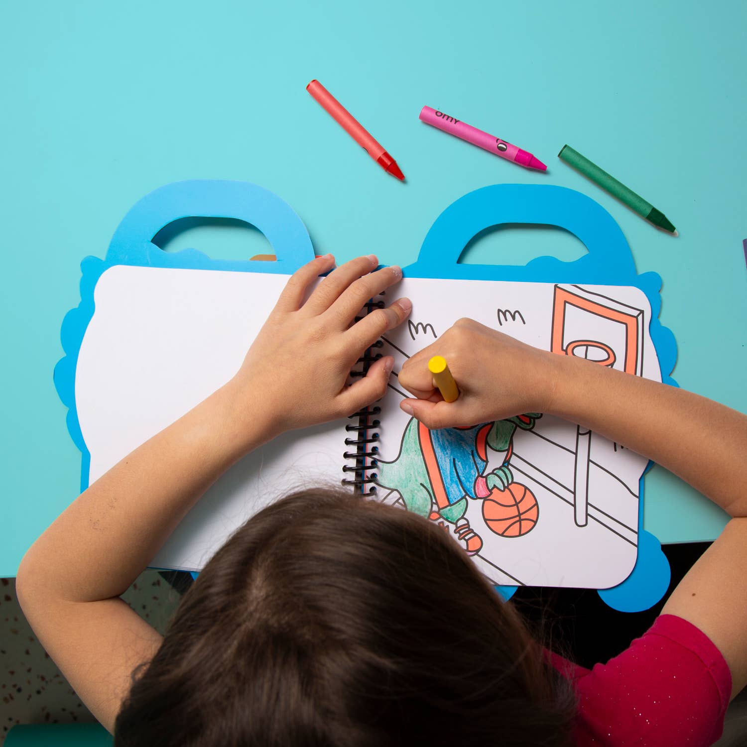 Child coloring a picture with crayons on a blue background